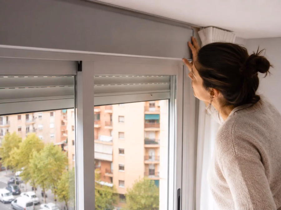 Caja de persiana en sección con ondas de ruido atravesando la tapa, la cinta, las guías y sus juntas